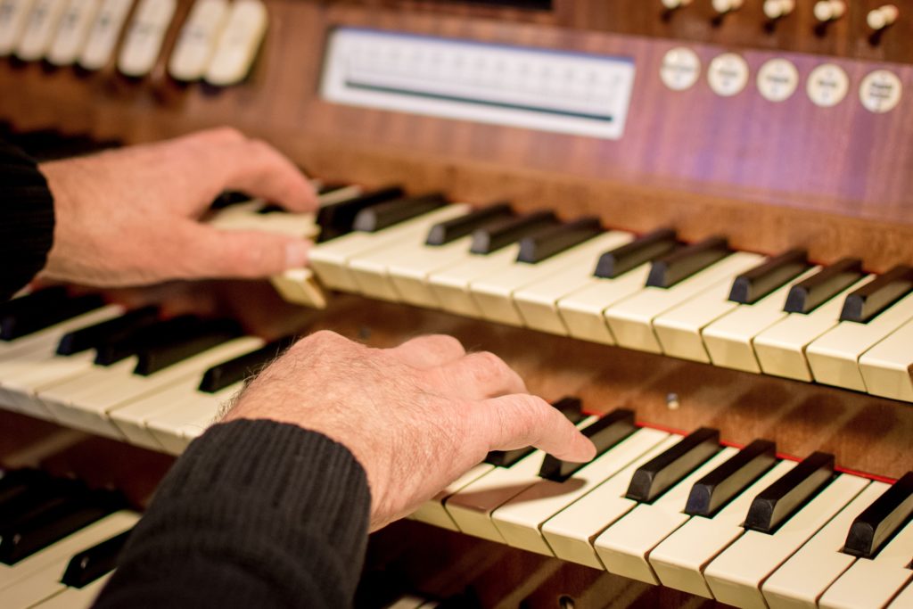 Hände spielen auf Tastatur einer Orgel